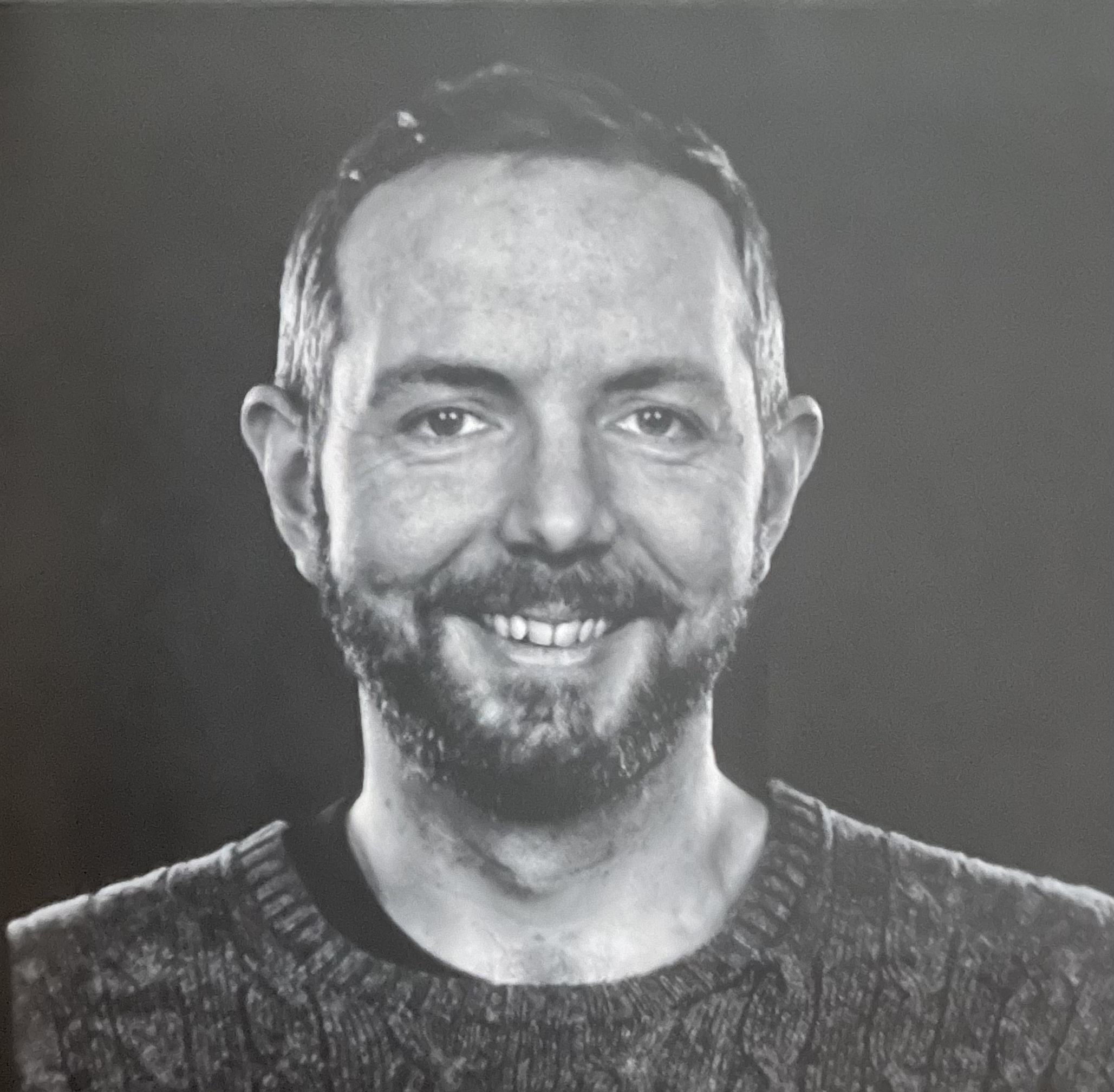 young man wearing shades and a hat with a beard, tattos and ear piercings